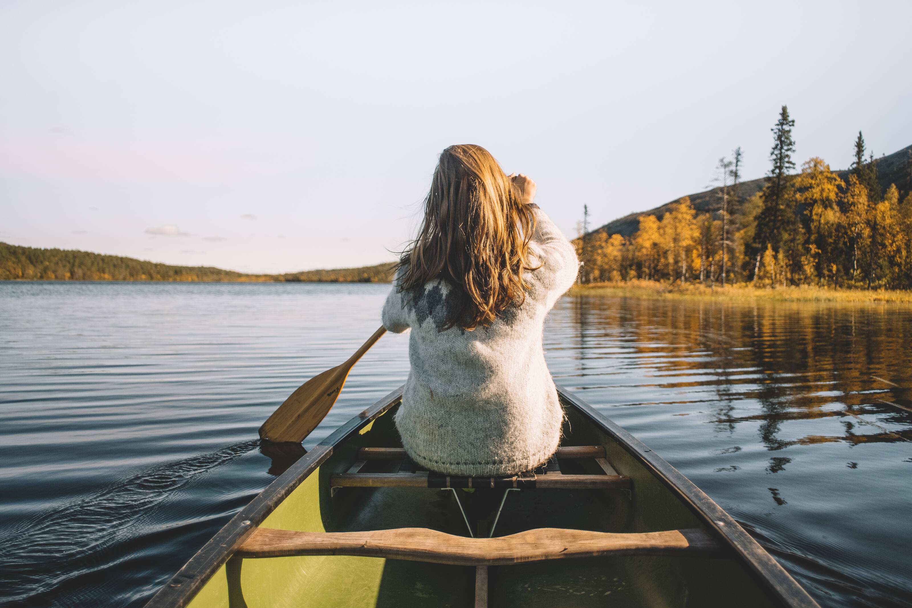 A women is paddling in a lake landscape in Finland.