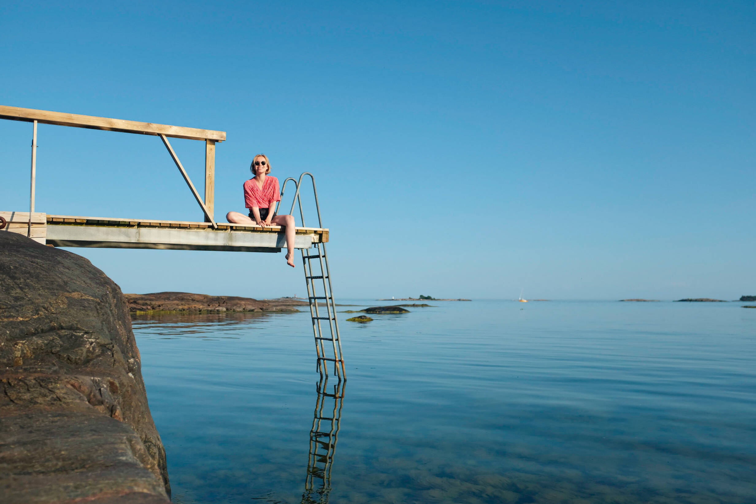 Frau, die auf einem Steg in Pihlajasaari, Helsinki sitzt