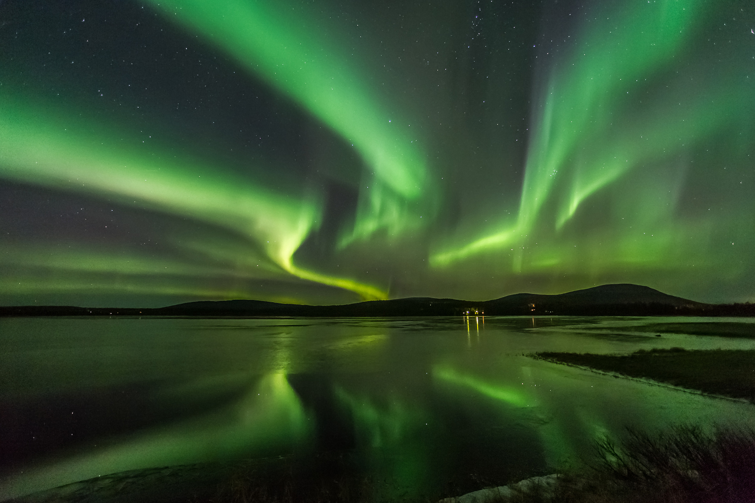 Nordlichter spiegeln sich auf einem See in Finnland.