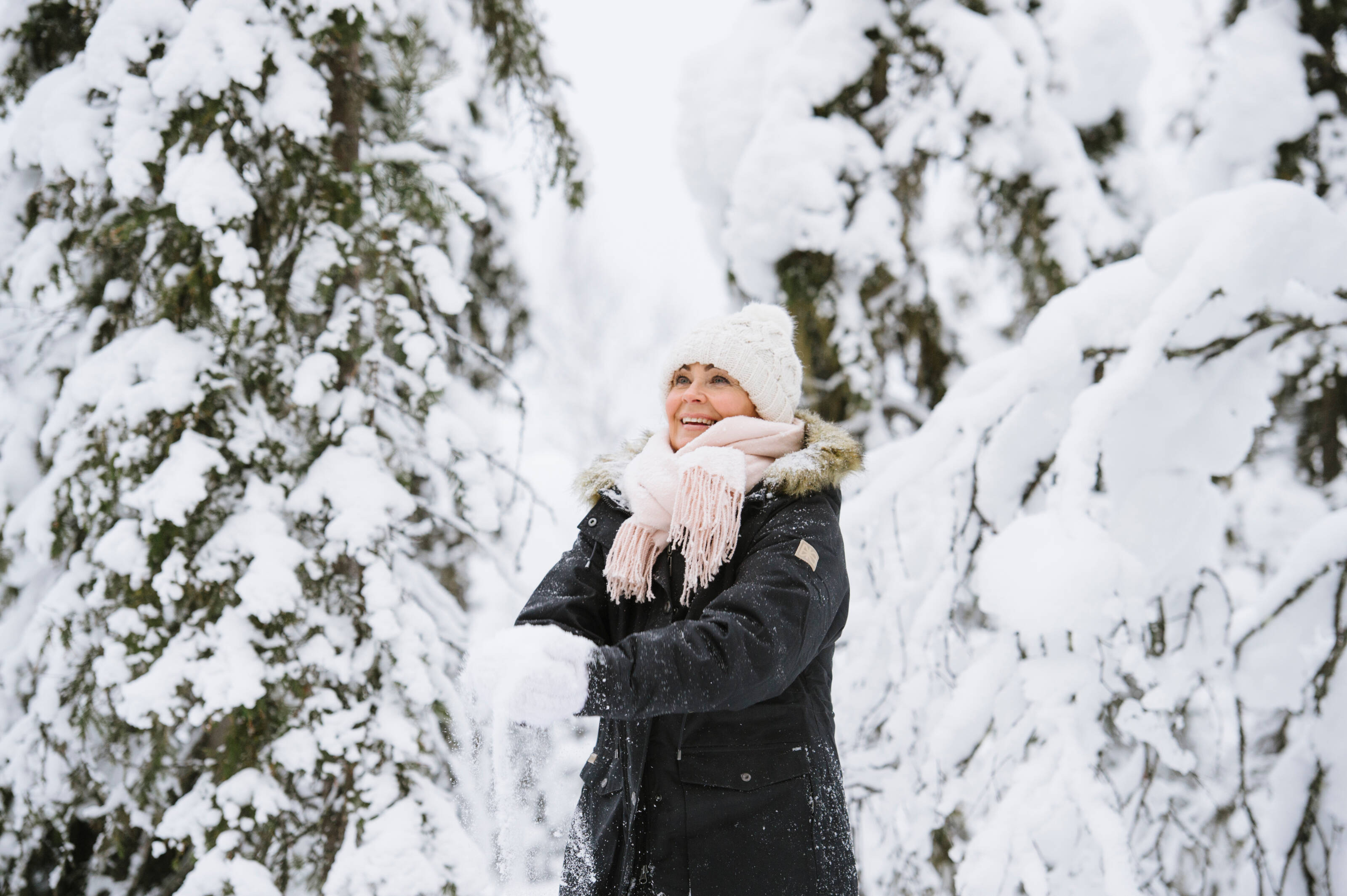 Mujer sonriente entre pinos nevados en Finlandia.