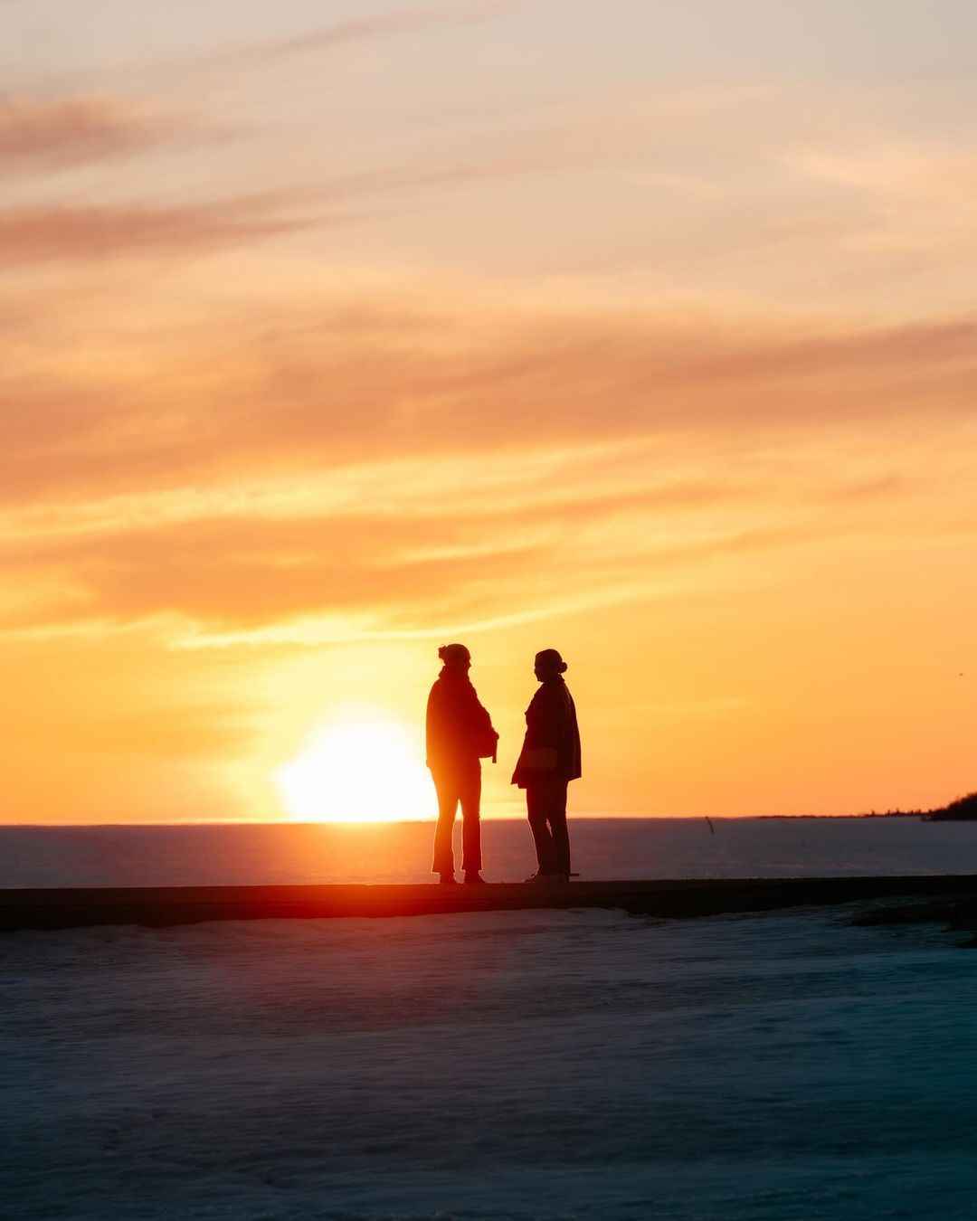 Menschen bei Sonnenuntergang am Strand von Nallikari in Oulu.