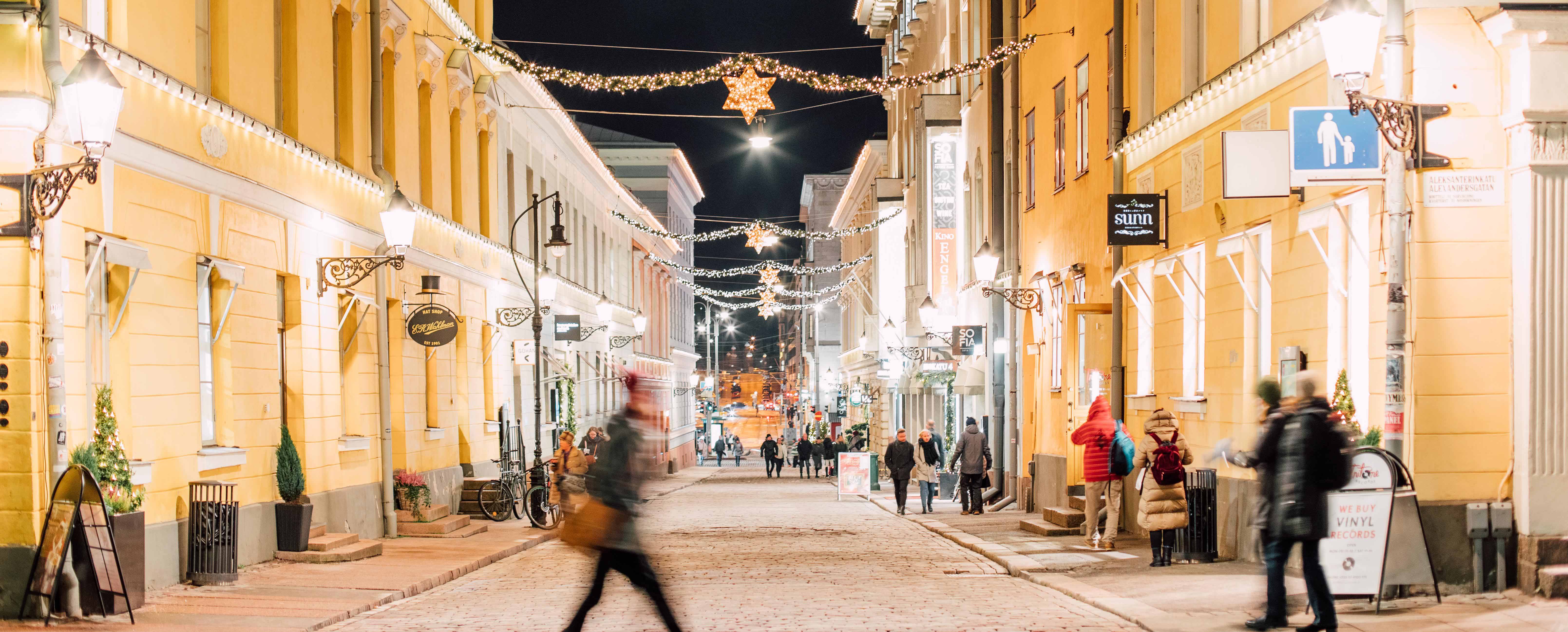 Straße voller Weihnachtslichter und und Menschen im Zentrum von Helsinki bei Nacht