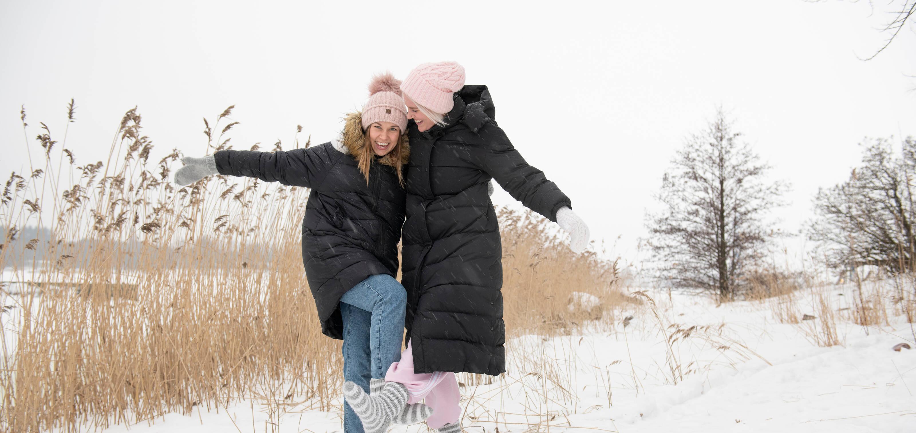 Zwei glückliche Frauen, die im Schnee lachen.