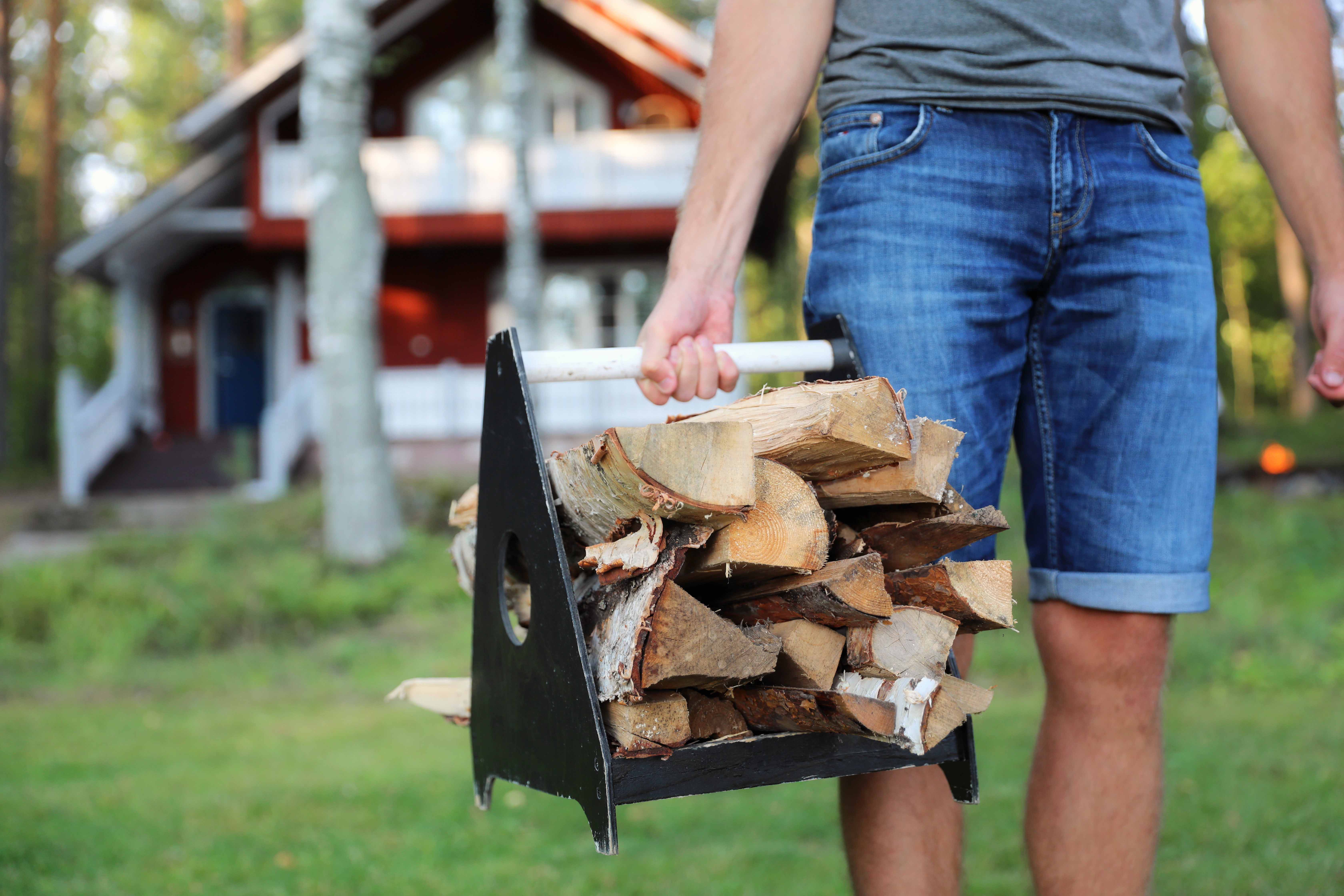 Ein Mann trägt Brennholz in eine finnische Sauna