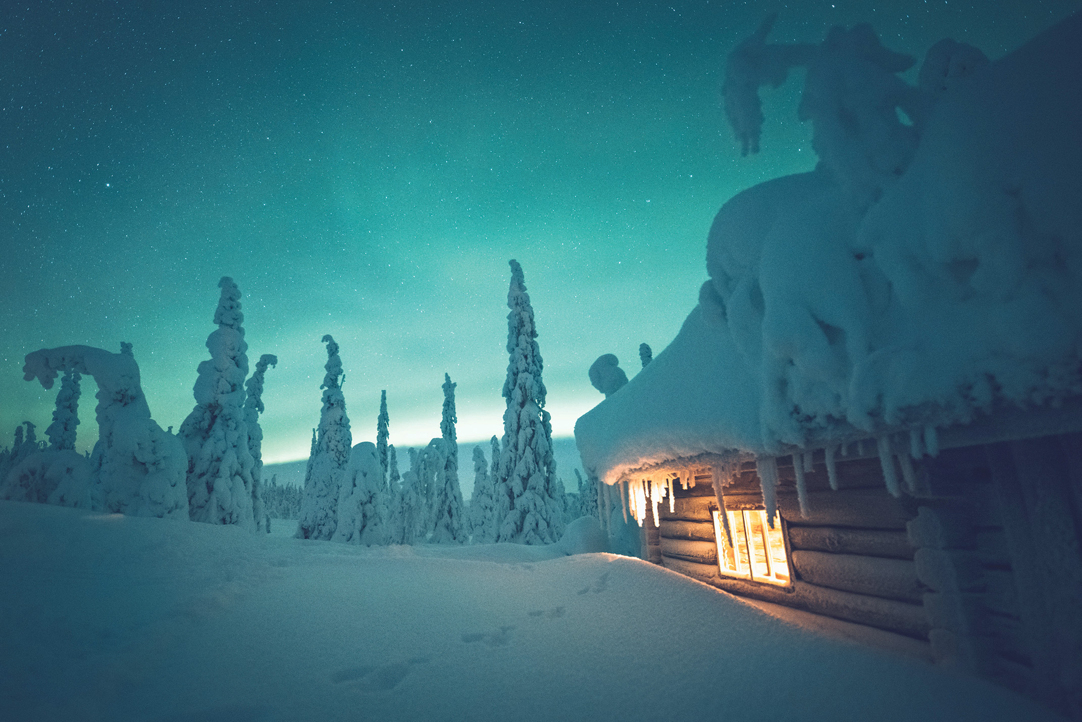 Aurore boreali sopra una cabina innevata in Lapponia, Finlandia.